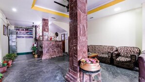 A reception area with a marble column, a sofa, a small table, and a potted plant.