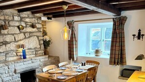 Un coin repas avec un mur en pierre, une table en bois, des chaises et une cheminée.