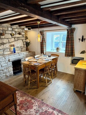 Ein Essbereich mit Steinwand, Holztisch, Stühlen und Kamin.