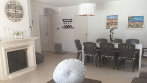 Un soggiorno con camino, un tavolo da pranzo con sedie, una sveglia e due quadri alle pareti.