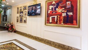 A hotel lobby with a large abstract painting, a television mounted on the wall, and framed photographs on the wall. - Senses Central Hotel (Ho Chi Minh City)
