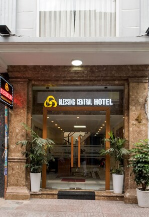 The entrance to the Blessing Central Hotel with a clear sign, potted plants, and a marble facade. - Senses Central Hotel (Ho Chi Minh City)