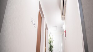 A hallway with white walls, a grey carpet, and a potted plant. - Hotel Cozy Taito Asakusa (Tokyo)