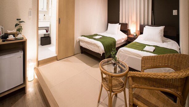 A hotel room with two beds, a small desk, a wicker chair, and a glass table. - Hotel Cozy Taito Asakusa (Tokyo)