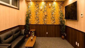 A room with a black leather sofa, a wooden coffee table, and a chandelier. - Hotel Cozy Taito Asakusa (Tokyo)