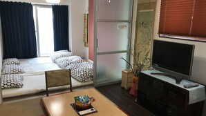 Ein kompakter Wohnraum mit Bett, Esstisch, Fernseher und kleiner Anrichte.