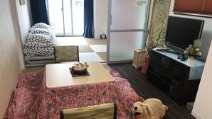 Ein gemütliches Zimmer mit Esstisch, Sofa, Fernseher und einem großen Hund.