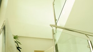Una escalera moderna con barandas de vidrio y un aplique decorativo en el techo.