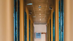 Un pasillo de hotel con una distribución larga y recta, con puertas distribuidas de manera uniforme y un diseño de techo consistente.