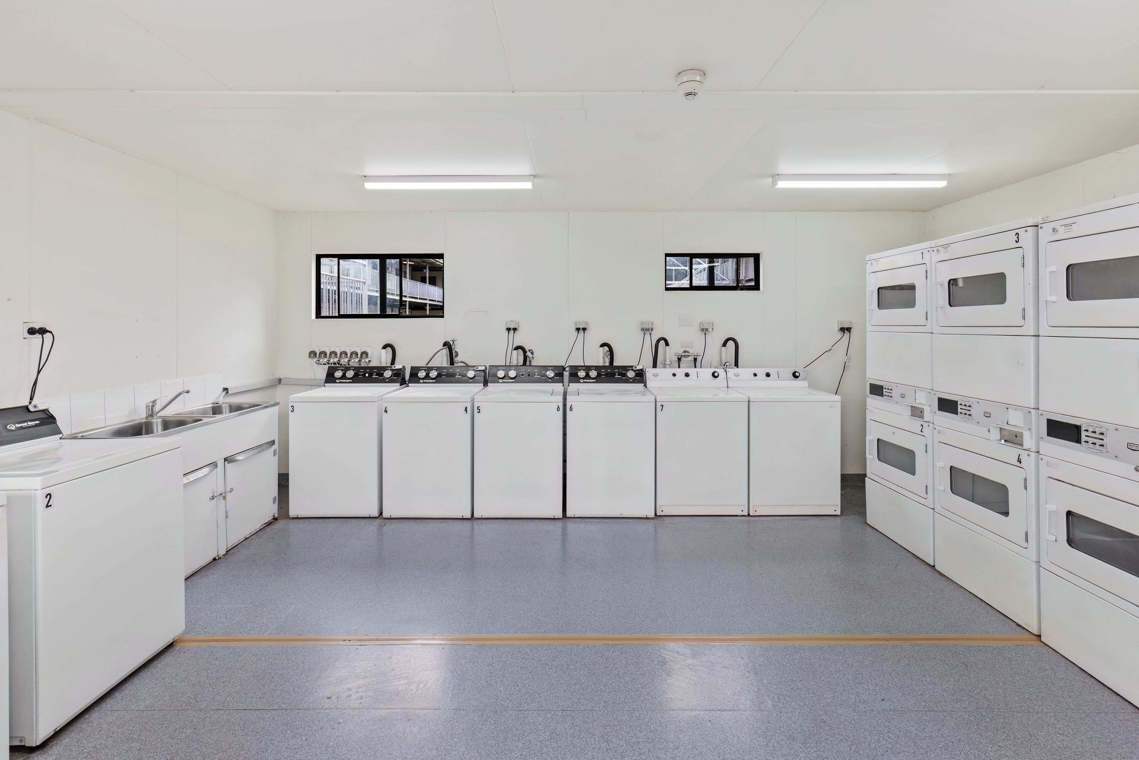 A kitchen with white cabinets, numbered appliances, and a central island with a sink and stove.