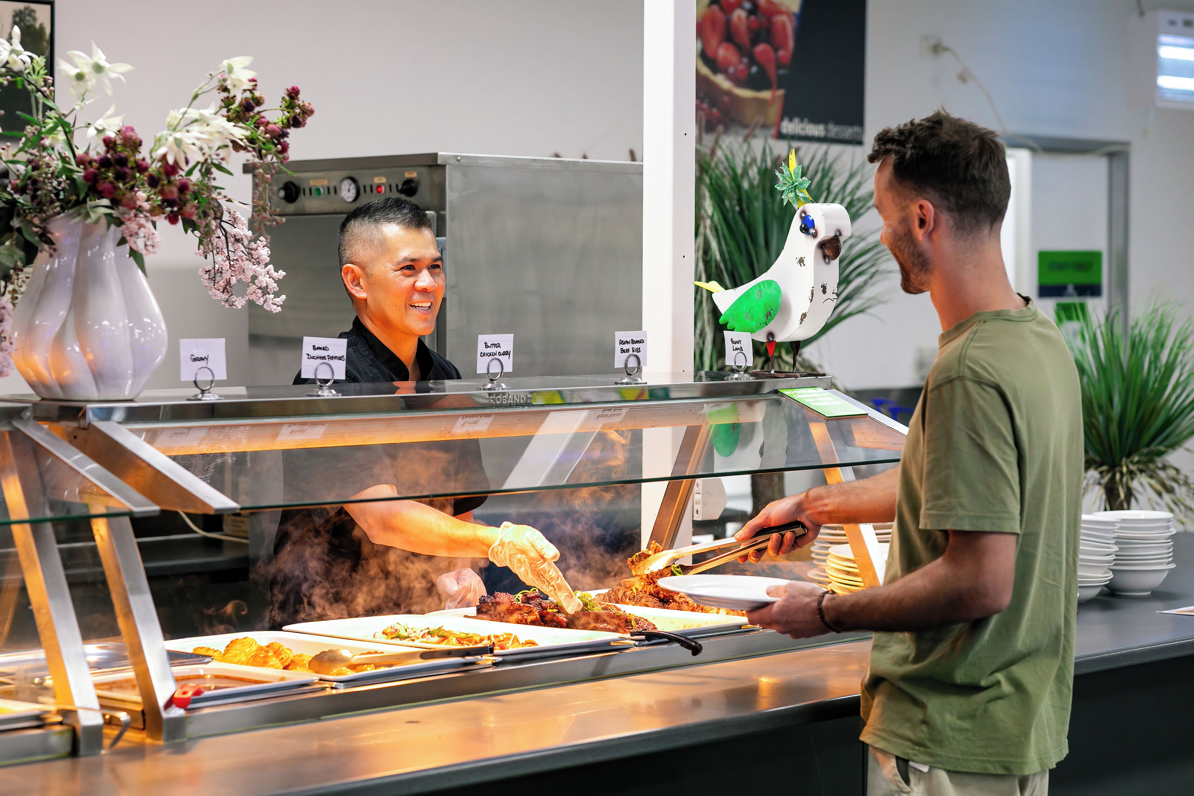 Un espace buffet proposant différents plats et un membre du personnel qui sert les aliments.