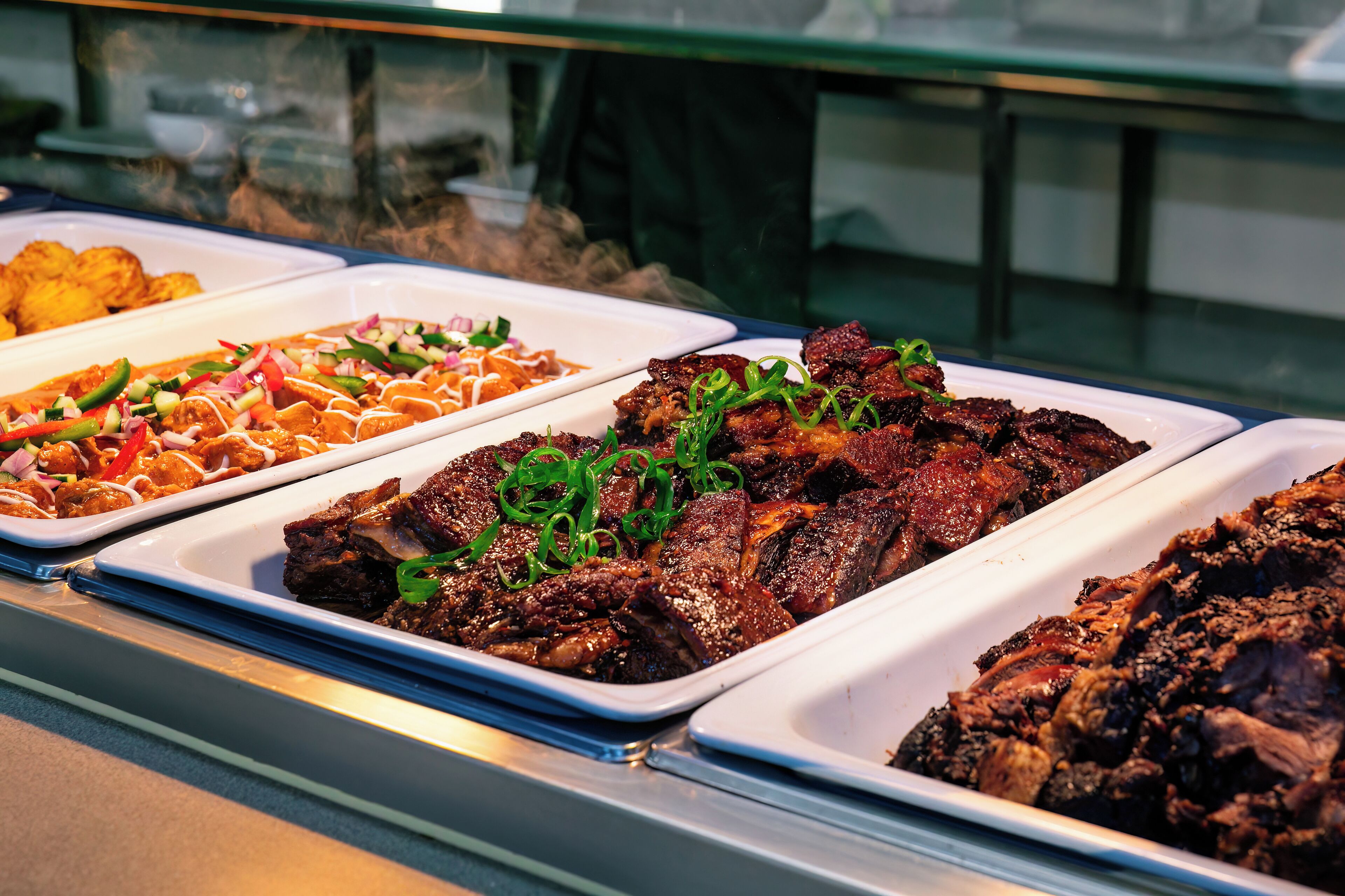 Un buffet proposant divers plats, notamment des viandes grillées et une salade.