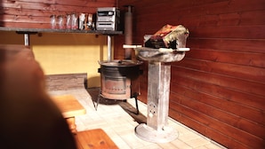 A rustic kitchen with a wood stove, a hanging shelf with glass jars, and a metal sink. - Apartmany u Slavky (Besenova)