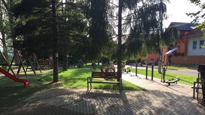 A playground with a red slide, a bench, and exercise equipment. - Apartmany u Slavky (Besenova)