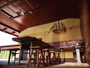 Interior em madeira com teto alto, um modelo de navio e um espaço de bar.