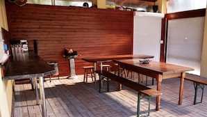 An outdoor patio with wooden tables and benches, a barbecue grill, and a brick floor. - Apartmany u Slavky (Besenova)