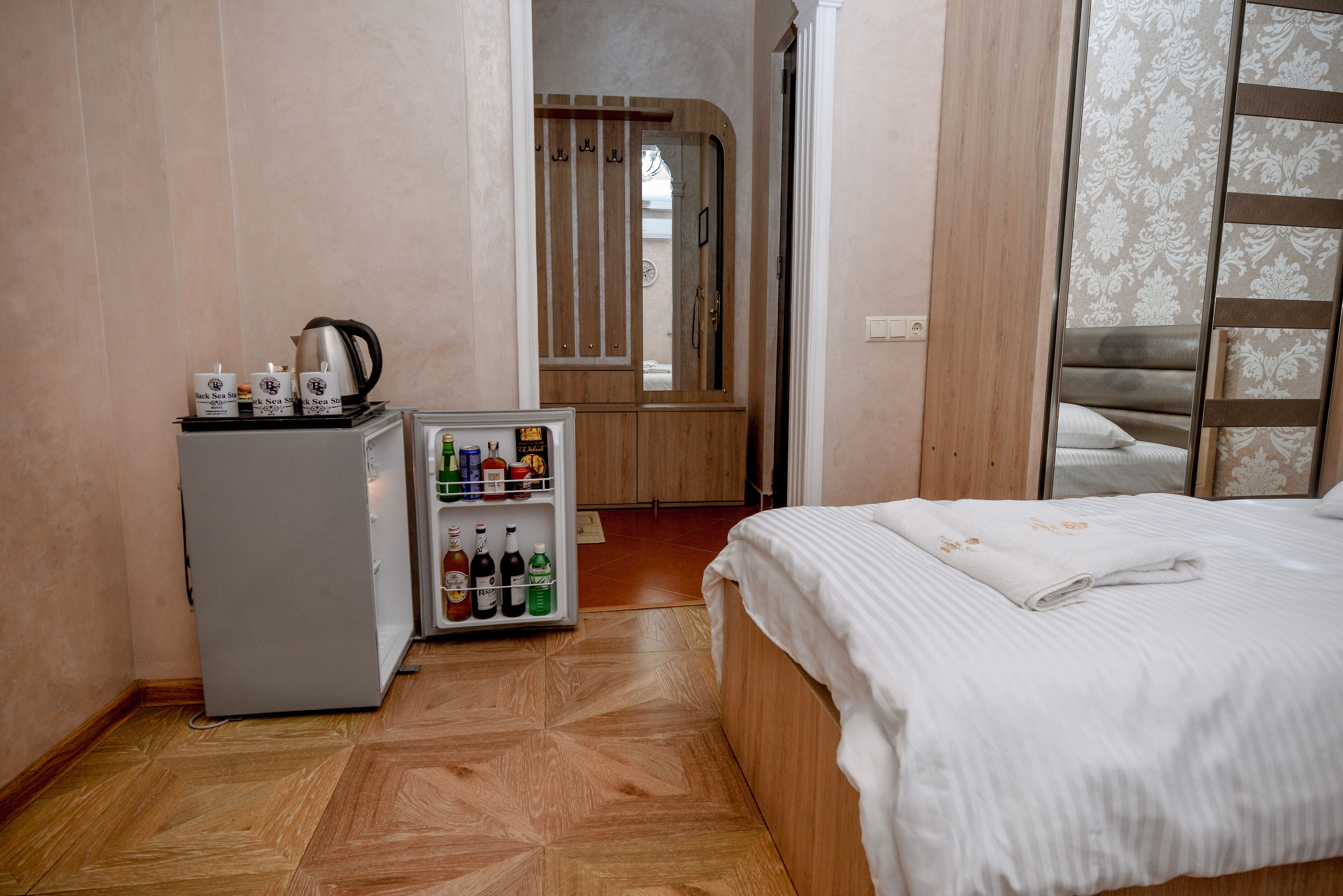 Ein Hotelzimmer mit Bett, Minibar, Holzschrank und Spiegel.