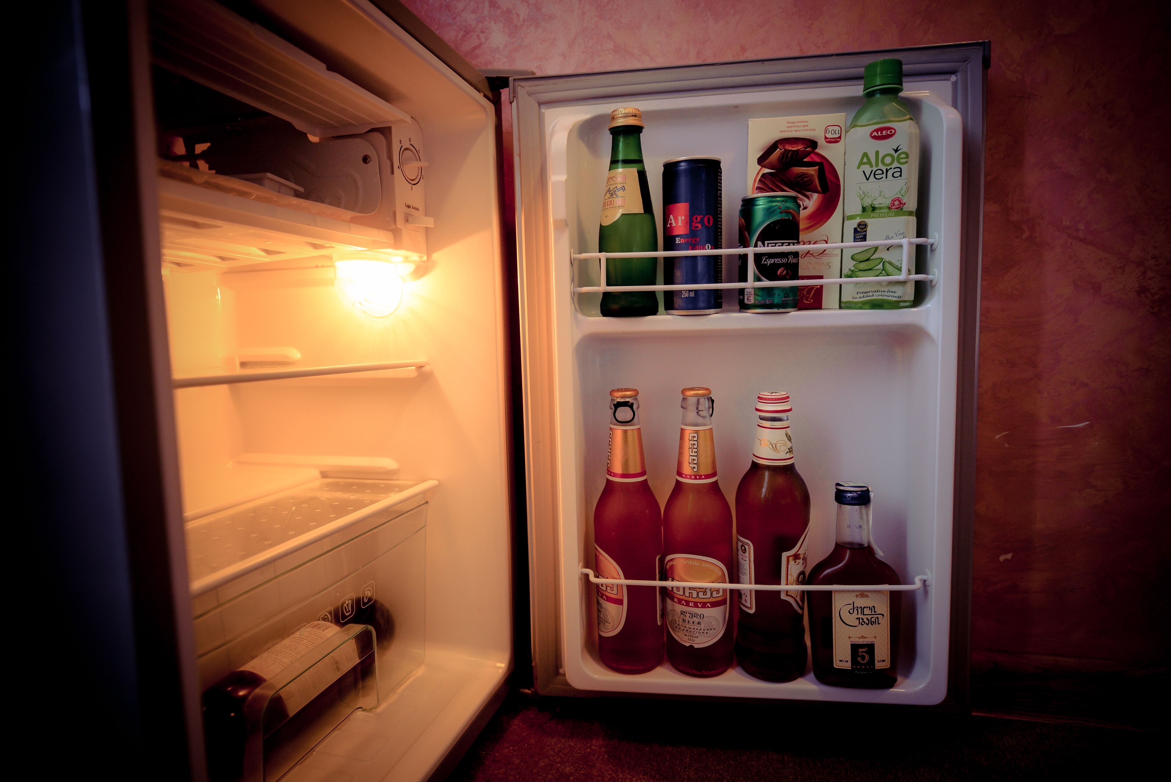 Un refrigerador abierto con diversas bebidas y condimentos.