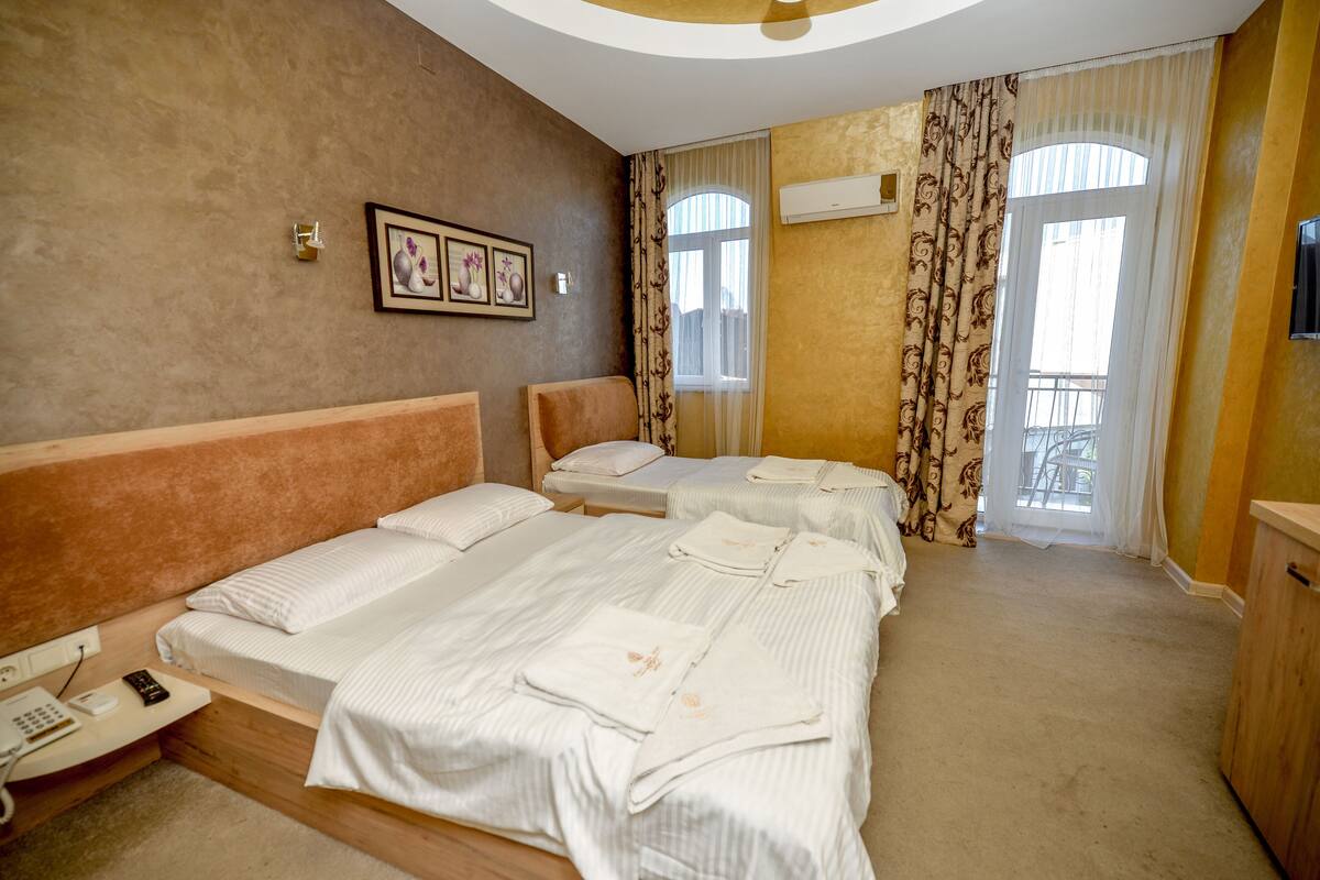 Hotellihuone, jossa on kaksi sänkyä, puhelin ja ikkuna, jossa on verhot.