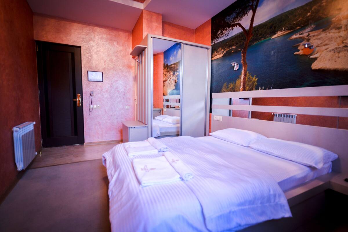 Hotellihuone, jossa on sänky, kylpyhuone ja näkymä rannikkomaisemaan.