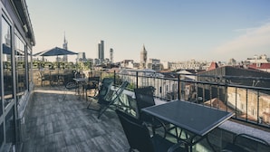A rooftop terrace with outdoor seating, a table, and a view of city buildings. - Black Sea Star Batumi (Batumi)