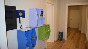 Un'area receptione con una scrivania, un telefono e un cartello che indica un punteggio di 9.9. Sono presenti scaffali con riviste e un cestino.