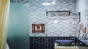 A bathroom with a toilet, a sink with a blue bowl, a towel rack, and a framed picture on the wall.