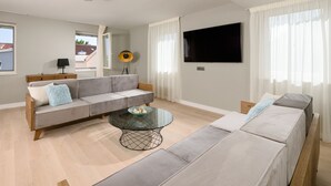 Una sala de estar moderna con un conjunto de sofá, una mesa de centro y un televisor de pantalla plana.