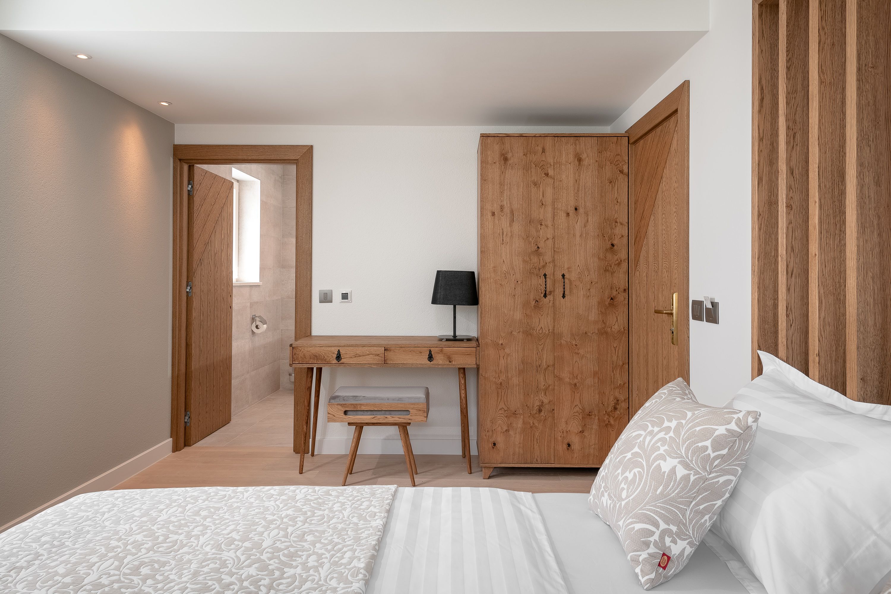 A bedroom with a bed, a desk, and a wardrobe.