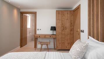 A bedroom with a bed, a desk, and a wardrobe.