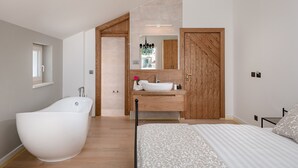 Un baño moderno con una bañera independiente, un tocador de madera y un espejo grande.