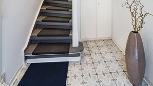 A modern staircase with a white railing and dark steps, leading to a landing with a white cabinet and a clock. - Boutique Hotel Rose Baden-Baden (Baden-Baden)