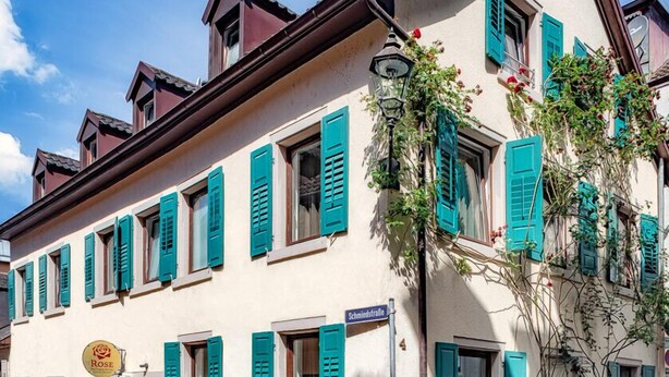 A traditional European building with multiple windows, a street sign, and a flower box. - Boutique Hotel Rose Baden-Baden (Baden-Baden)