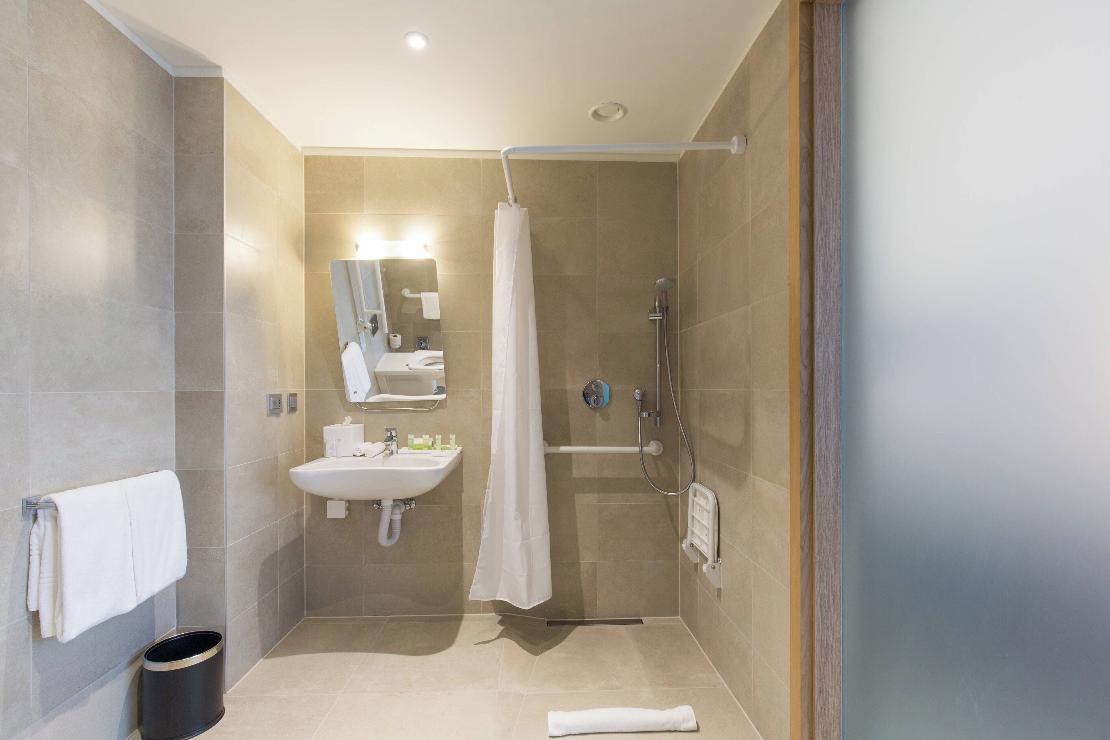 A modern bathroom with a shower, sink, and mirror.
