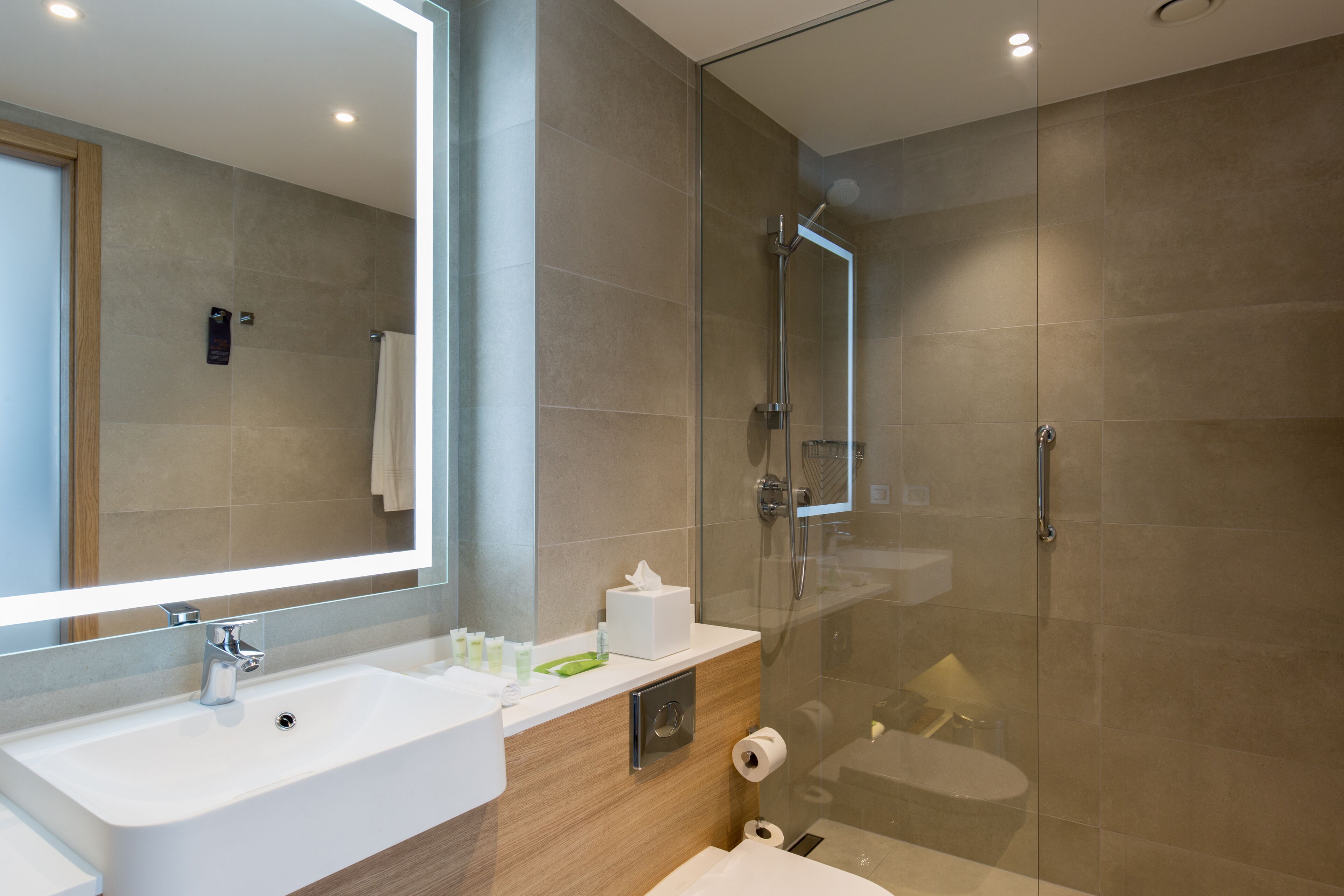 A modern bathroom with a glass-enclosed shower, a large mirror, and a white sink.