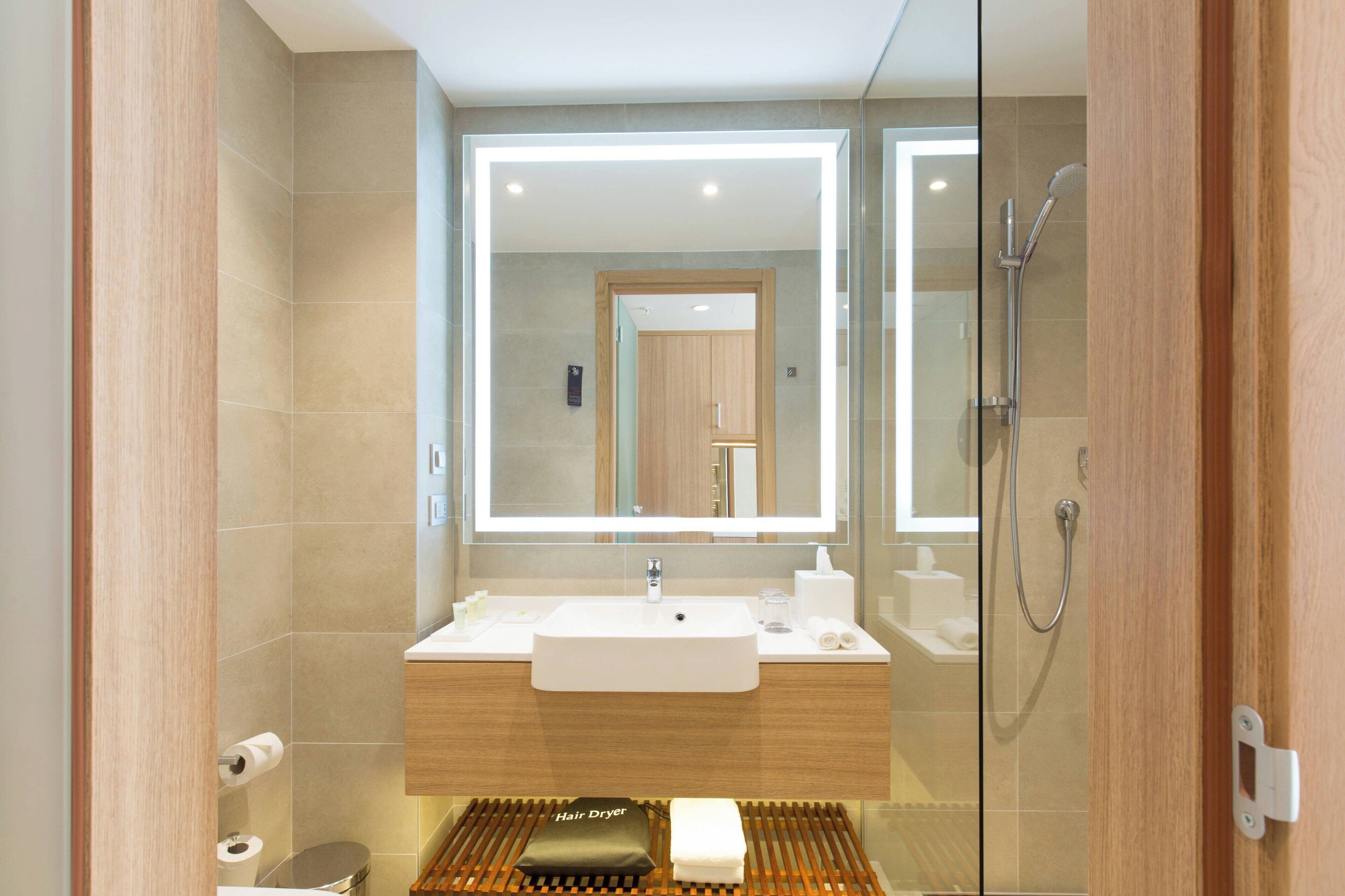 A modern bathroom with a large mirror, a sink, and a shower.