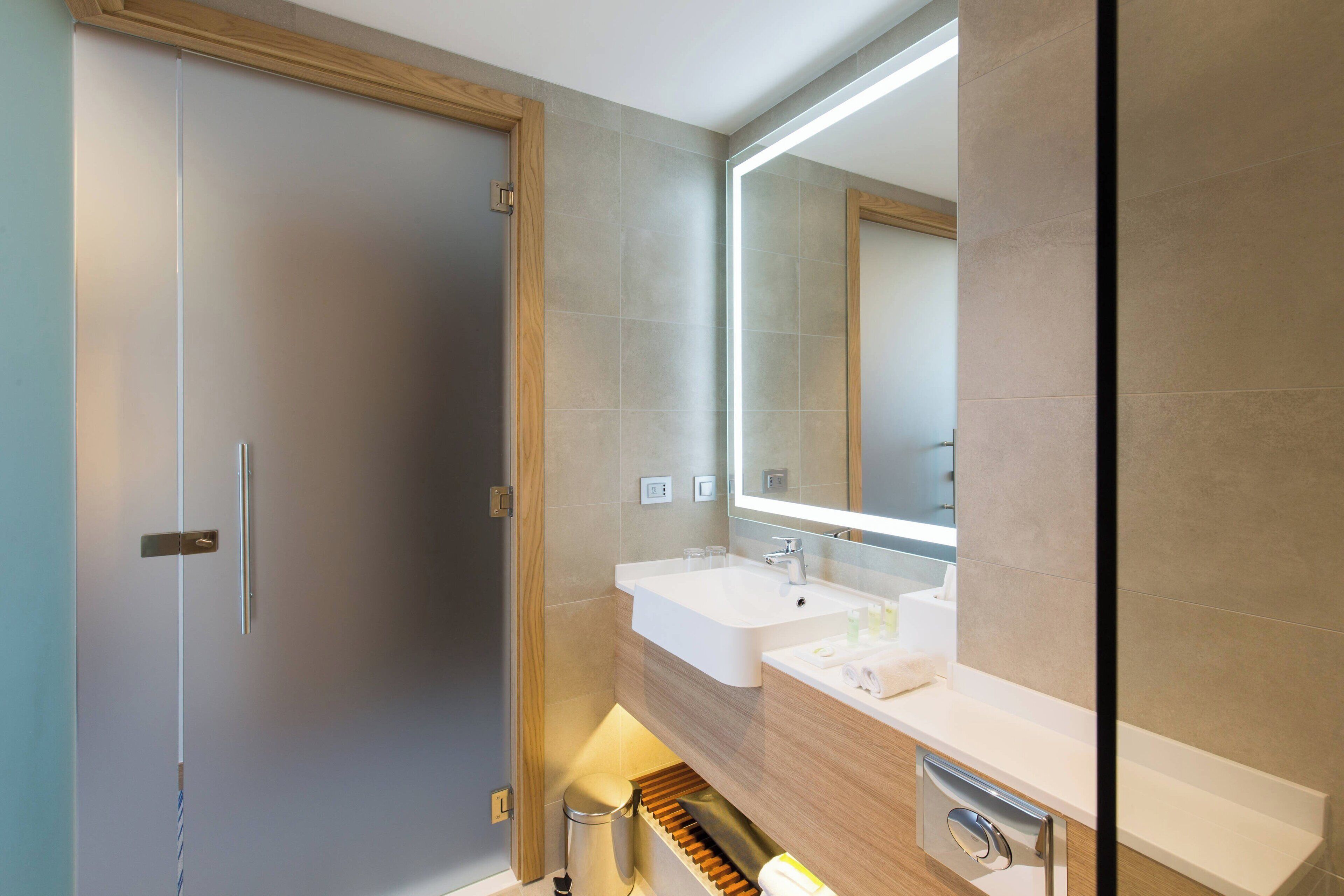 Un baño moderno con dos lavamanos, un espejo grande y una puerta de madera.