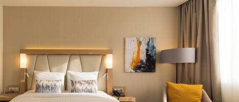A hotel room with a large bed, two bedside tables, a chair, a lamp, and a painting on the wall.