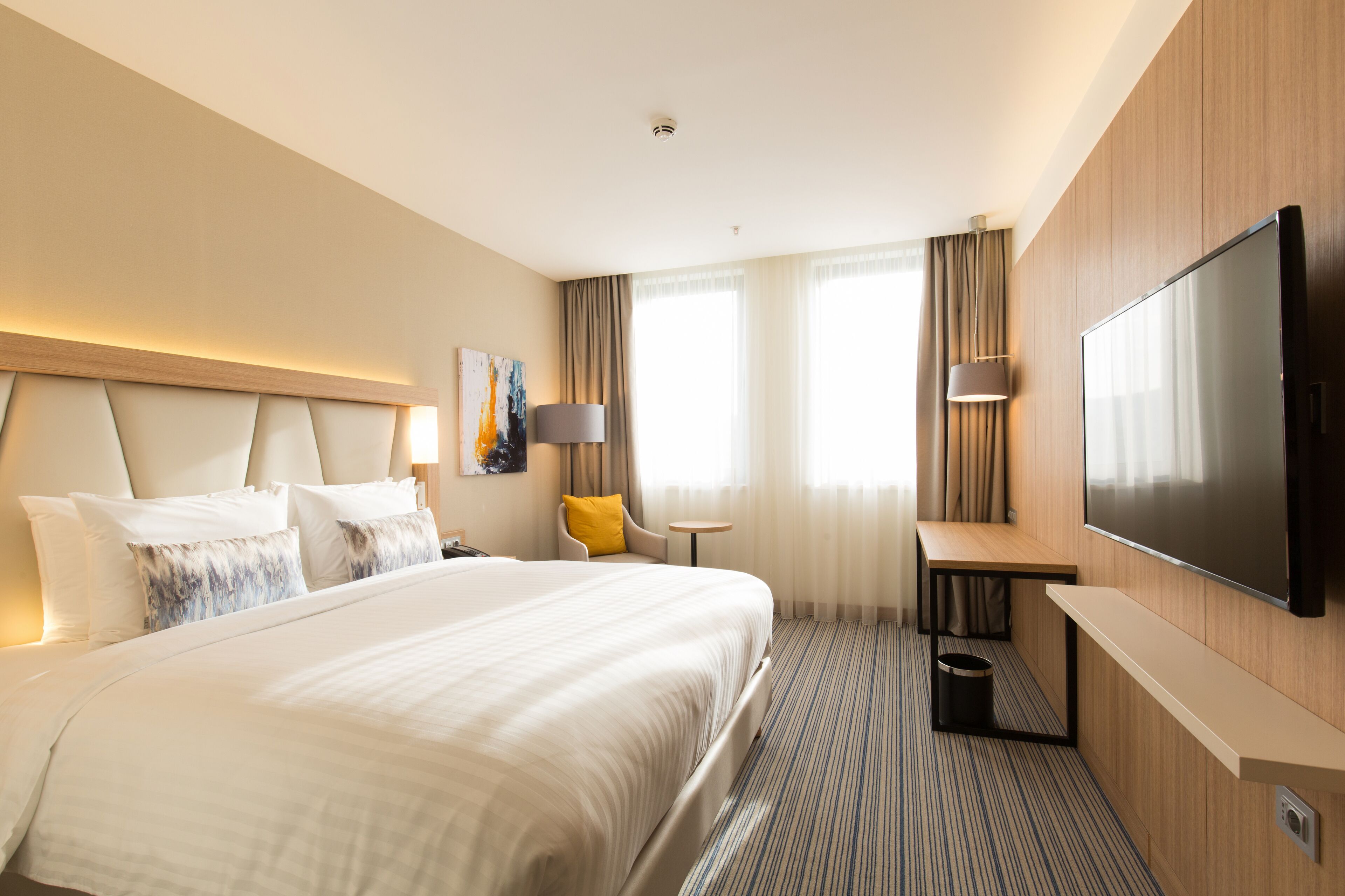A hotel room with a large bed, a flat-screen TV, a desk, and a chair.