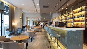 Eine moderne Bar mit einer langen Theke, Barhocker und einer Auswahl an Spirituosen.
