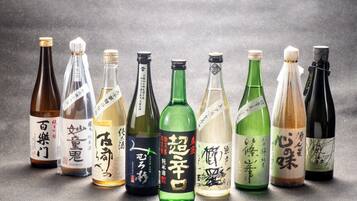 Eine Auswahl an Sake-Flaschen mit japanischen Etiketten, angeordnet auf einer strukturierten Oberfläche.