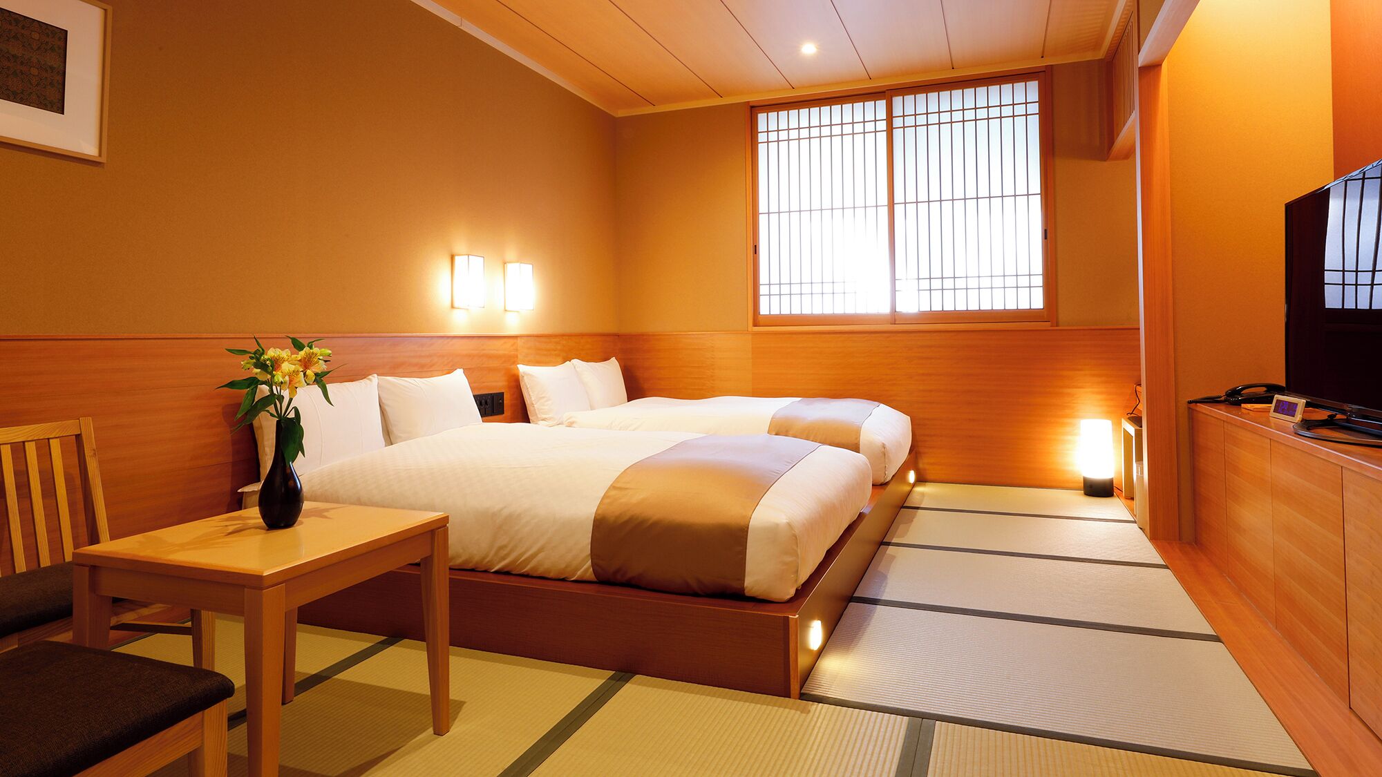 A hotel room with two beds, a desk, a chair, a TV, and a window with a view.