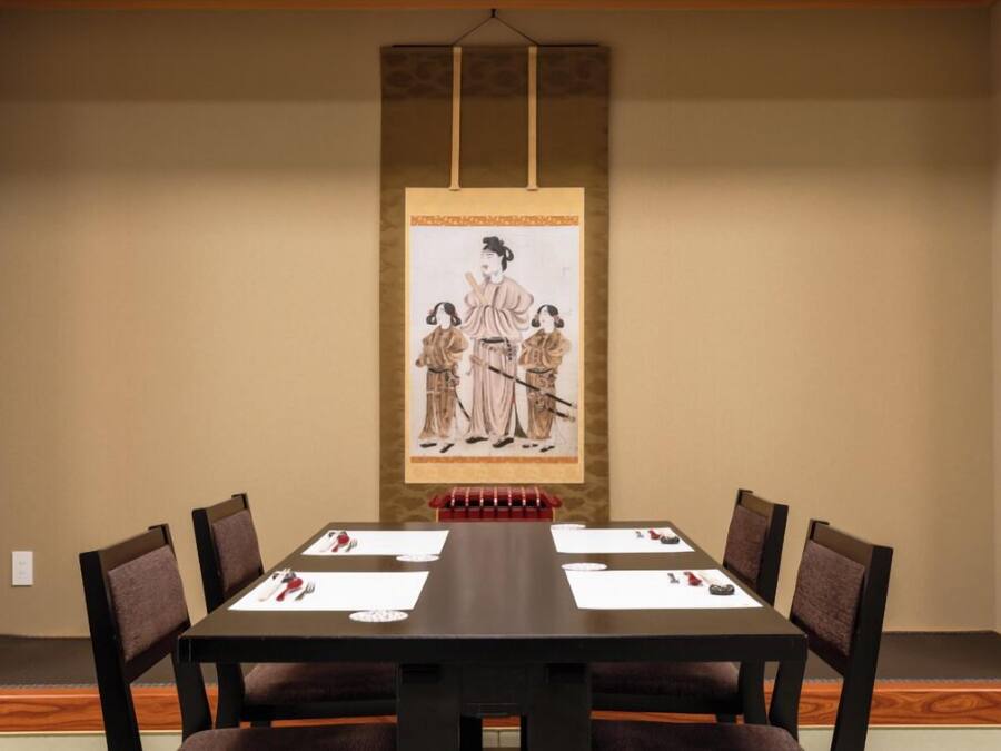 Un salón de conferencias con una larga mesa, seis sillas y una pintura tradicional asiática en la pared.