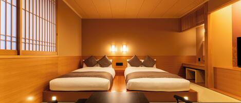 A hotel room with two beds, a wooden table, and a TV.