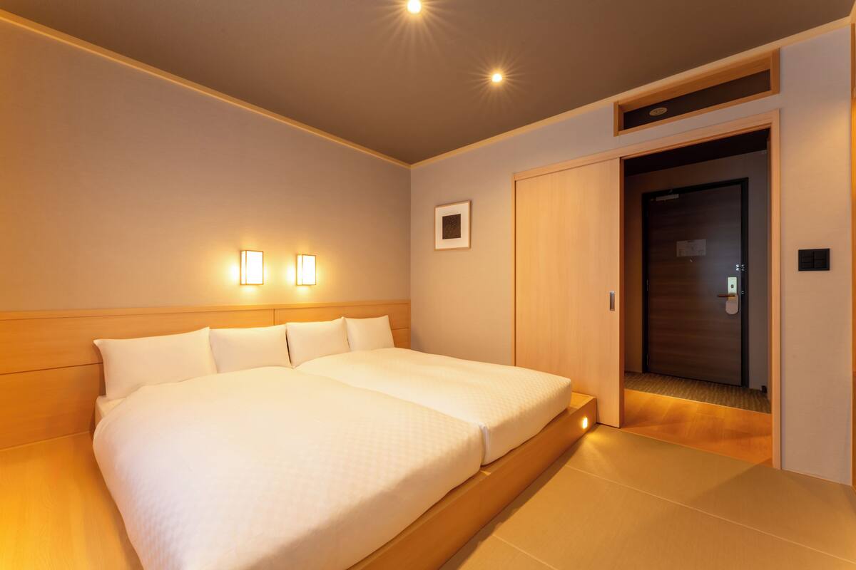 A double bed with a wooden headboard, two bedside lamps, and a small framed picture on the wall.