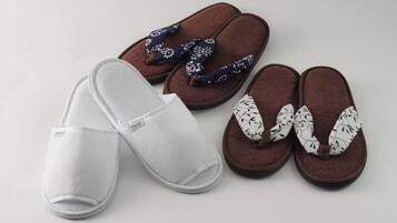 A pair of white slippers, a pair of brown slippers with floral patterns, and a pair of brown slippers with black leaf patterns.