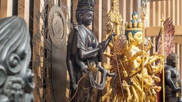 Una estatua de una deidad con múltiples brazos, rodeada de decoraciones elaboradas y otras estatuas.