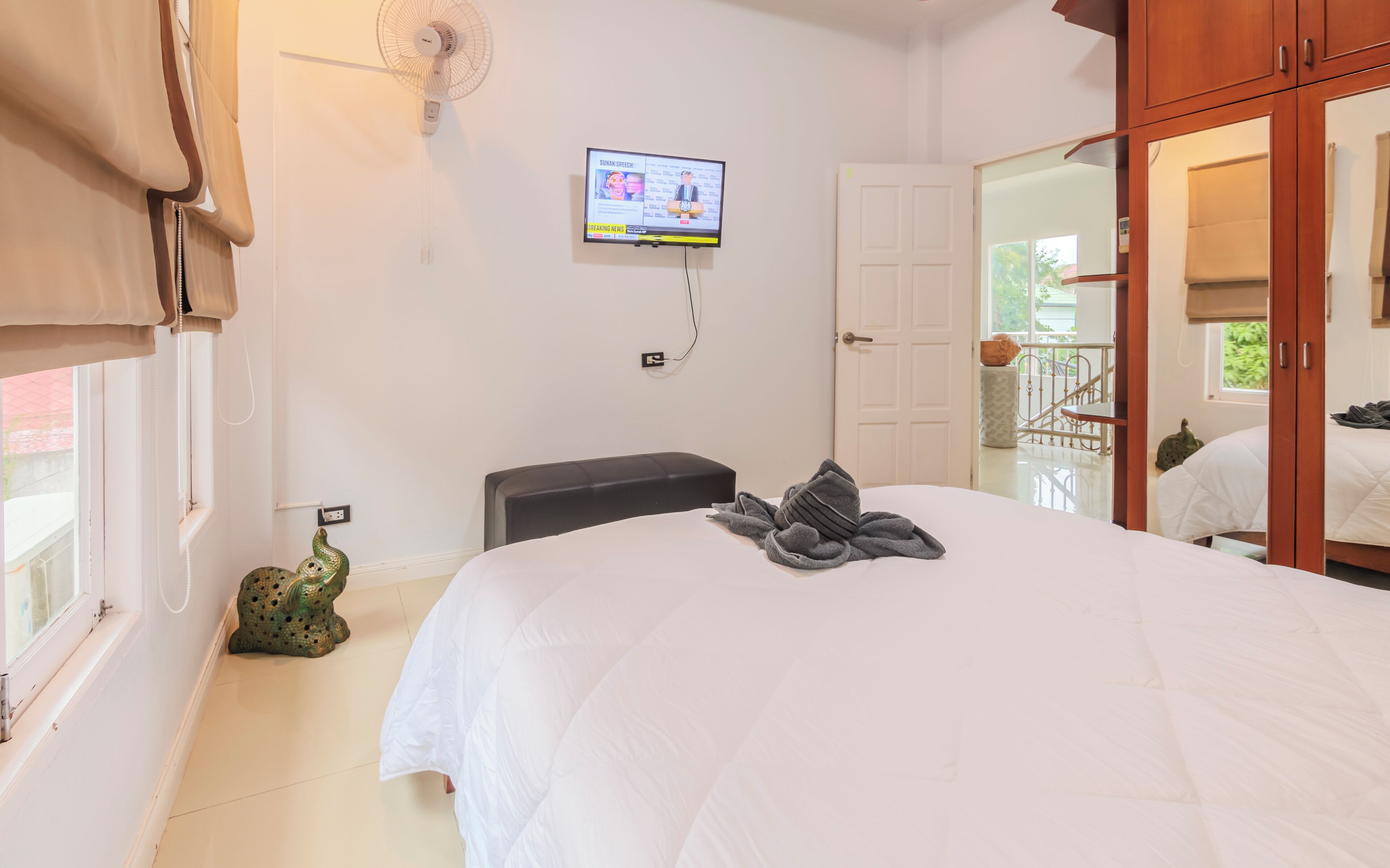 Un dormitorio con cama, televisión montada en la pared, armario y ventana con vistas al exterior.