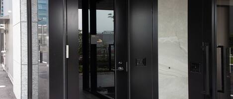 A modern building entrance with a glass door, a metal handle, and a small sign above the door.