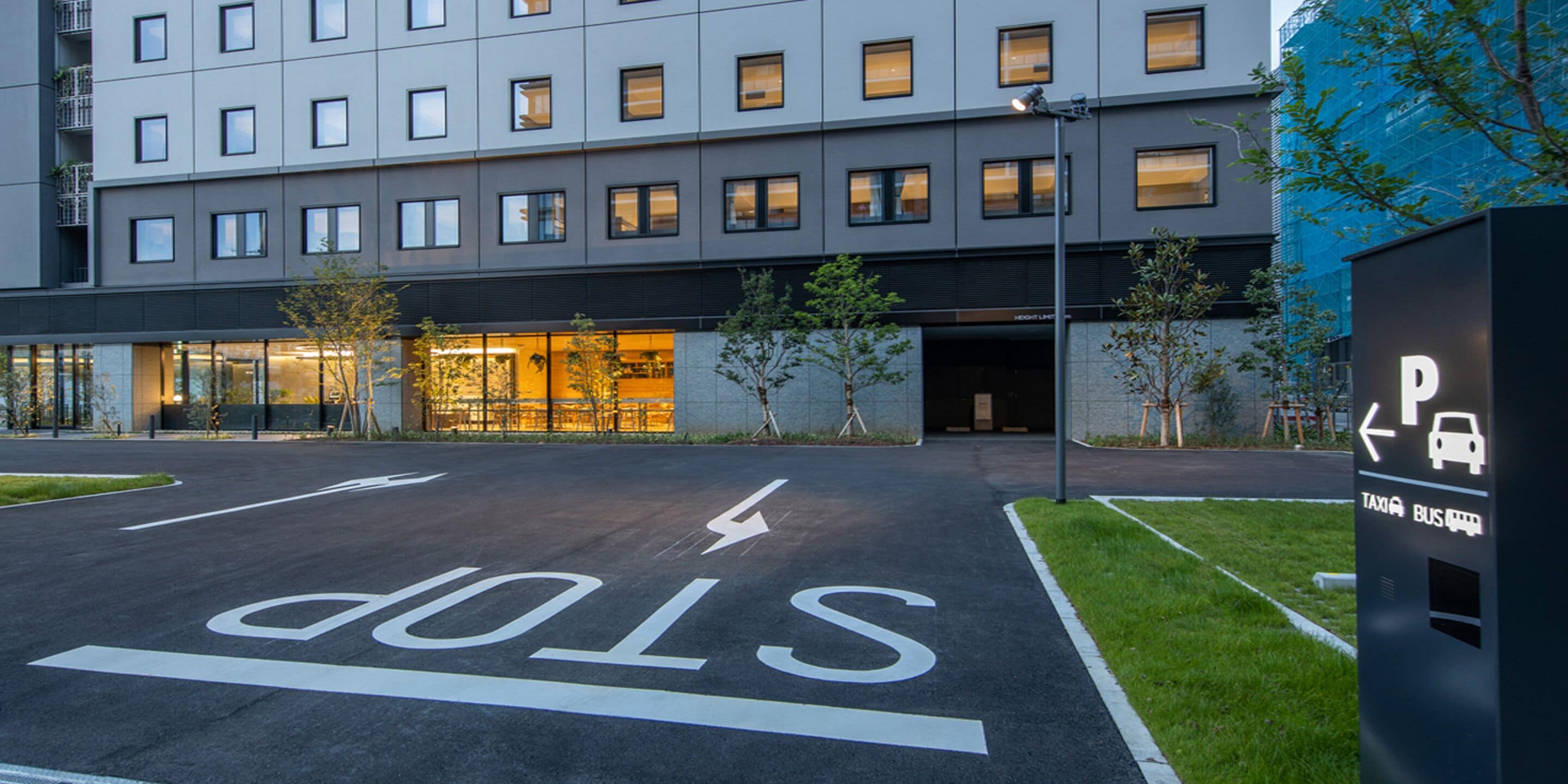 A modern building with a parking area marked with a stop sign and directional arrows.